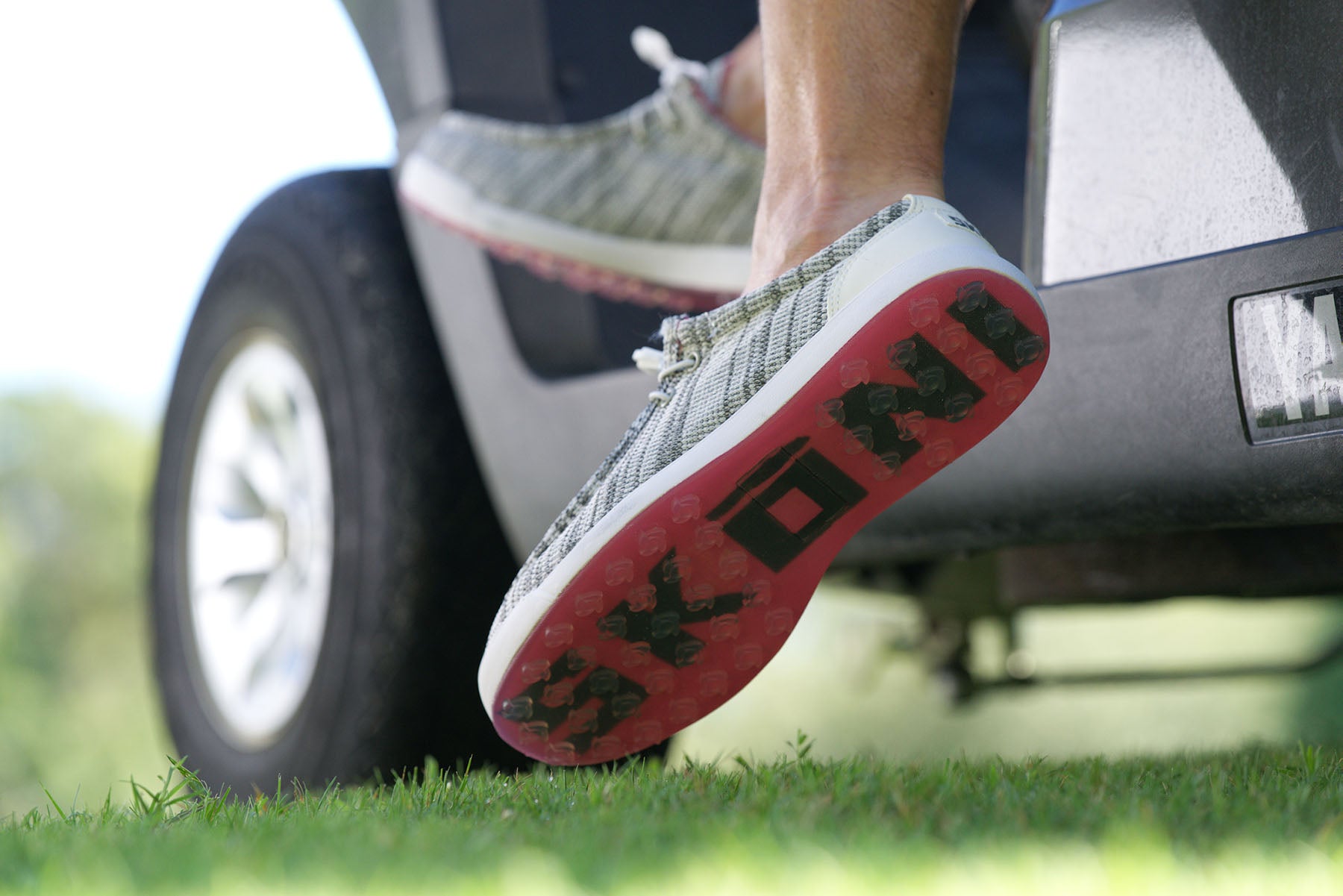 Colorful and comfortable SKŌNI golf shoes worn on a golf cart